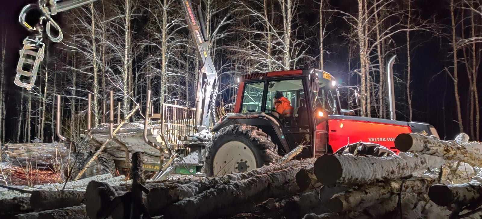Metsäkuormain työvaloissa talvi-illan korjuutyömaalla
