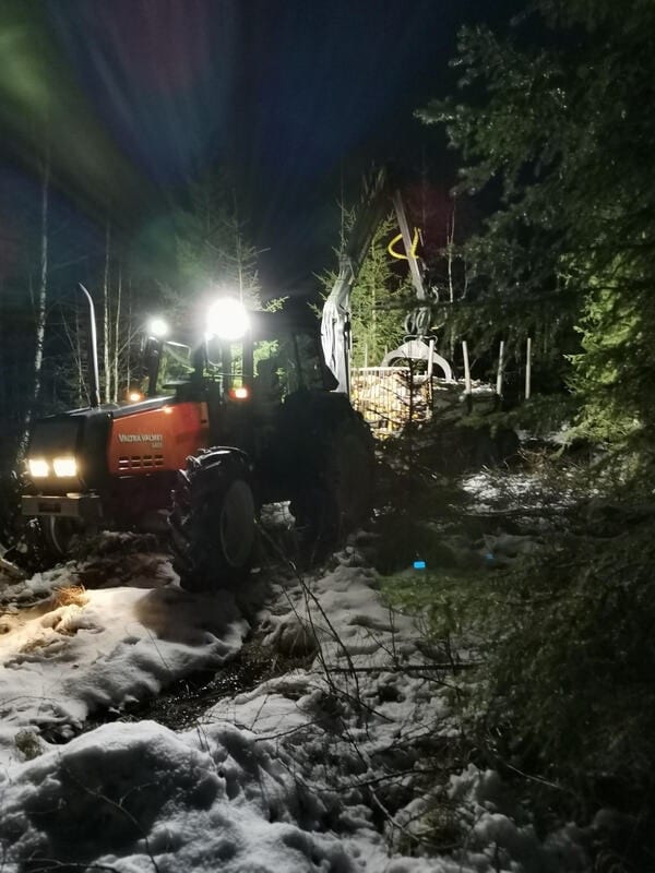 Traktori työvaloissa metsätiellä pimeällä