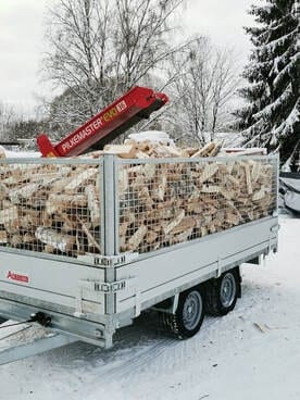 Peräkärry täynnä kuivaa koivuklapia talvipihalla